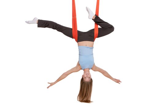 Young woman upside down doing anti-gravity aerial yoga in hammock on a seamless white background.