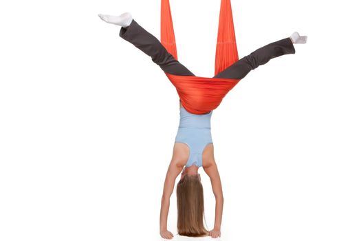 Young woman making antigravity yoga exercises with red hammock on a white background