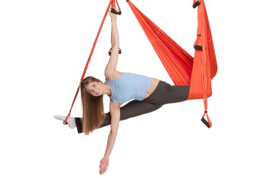 Young woman upside down doing anti-gravity aerial yoga in hammock on a seamless white background.