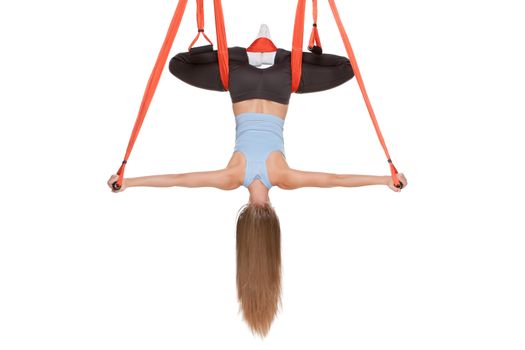 Young woman upside down doing anti-gravity aerial yoga in hammock on a seamless white background.