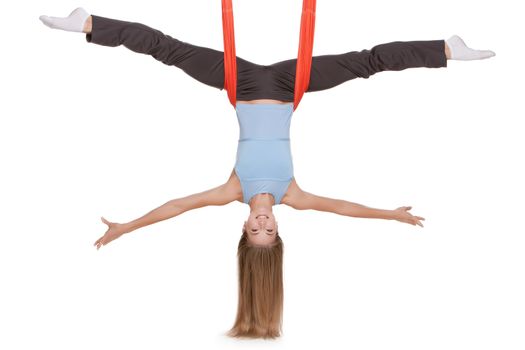 Young woman making antigravity yoga exercises with red hammock on a white background