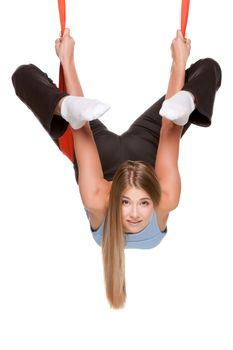 Young woman doing anti-gravity aerial yoga in red hammock on a seamless white background.