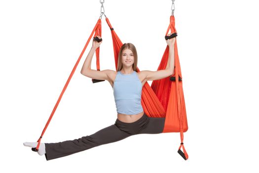 Young woman making antigravity yoga exercises with red hammock on a white background