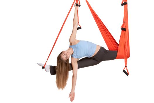 Young woman upside down doing anti-gravity aerial yoga in hammock on a seamless white background.