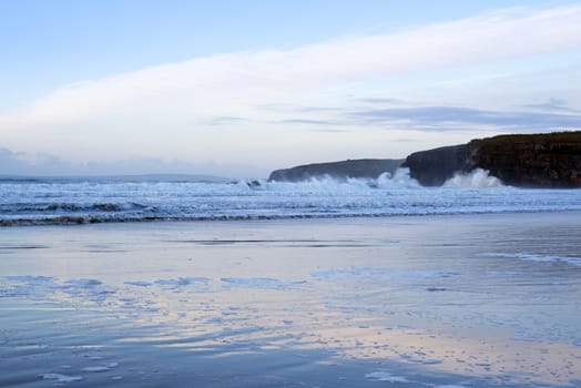 winter waves crashing onto the beach cliffs at ballybunion