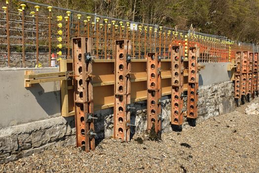 Metal supports hold in shuttering against a new concrete structure with steel rods.