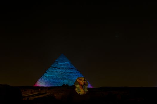 A row of camels transport tourists in front of all of the Giza Pyramids in Cairo, Egypt