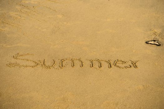 Inscription of summer on wet beach sand