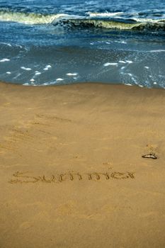 Inscription of summer on wet beach sand