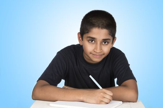 An handsome Indian kid doing his homework diligently
