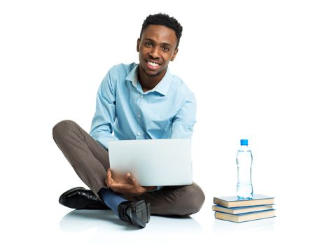 Happy african american college student with laptop, books and bottle of water sitting on white background