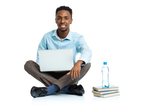 Happy african american college student with laptop, books and bottle of water sitting on white background