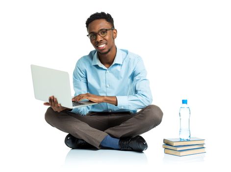 Happy african american college student with laptop, books and bottle of water sitting on white background