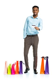 Happy african american man with shopping bags and holding credit card on white background. Holidays concept