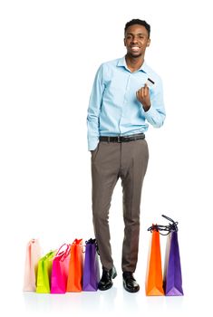 Happy african american man with shopping bags and holding credit card on white background. Holidays concept