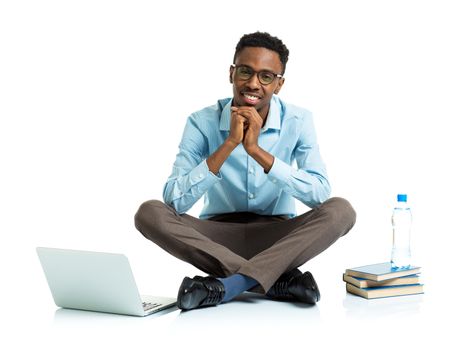 Happy african american college student with laptop, books and bottle of water sitting on white background