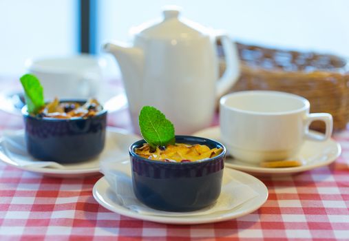 Fruit pudding with mint and tea on a checkered tablecloth