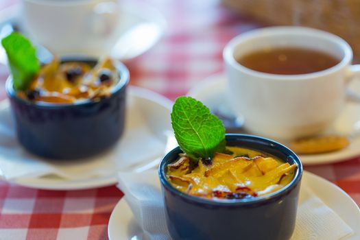 Fruit pudding with mint and tea on a checkered tablecloth