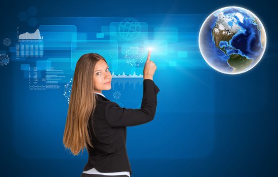 Businesswoman standing back and looking at camera pressing on holographic screen with graphical charts. Earth in upper right corner. Elements of this image furnished by NASA