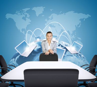 Businesswoman standing behind chair and looking at camera on abstract background with computers and earth model. Elements of this image furnished by NASA