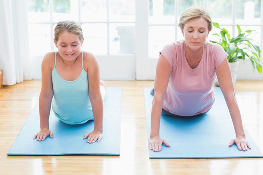 Mother and daughter doing yoga at home in living room 