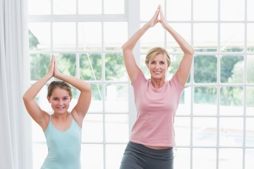 Mother and daughter doing yoga at home in living room 