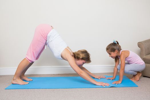 Mother and daughter doing yoga at home in the living room