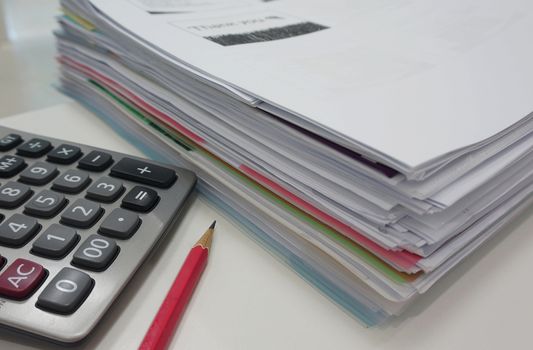 Pile of document, pencil and calculator on desk in office.                                 