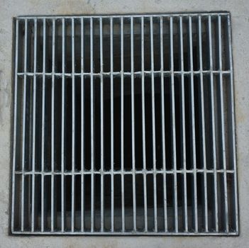 Sewer grate made of steel rectangular shaped on the roadside.                               