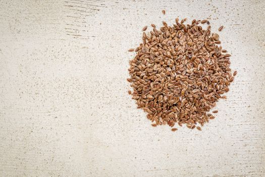 a small pile of brown flax seeds on a white painted, rustic barn wood with a copy space