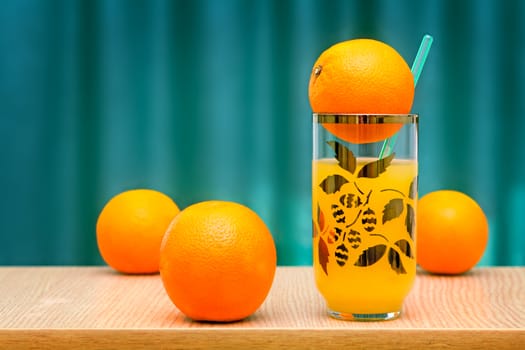 Fresh orange juice in the glass and some oranges on the table..