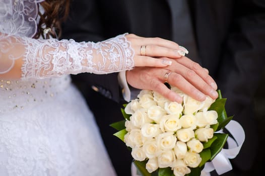 Hands and rings and wedding bouquet.