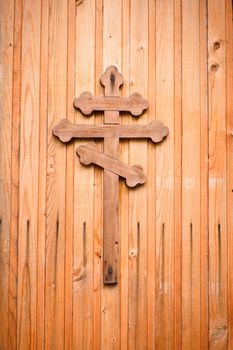 Wooden cross with silver detail representations of the Crucifixion on green background.