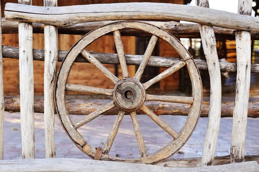 old wood coach wheel around barn in village