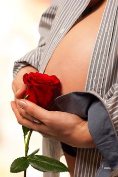 Pregnant woman hands holding a red rose in front of her abdomen. Image isolated with work path.
