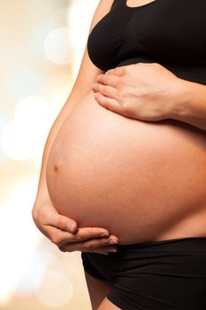 Pregnant woman holding gently her belly with two hands. Isolated background with work path, vertical image.