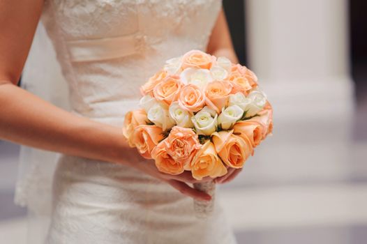 bride holding a wedding bouquet with white and pink roses