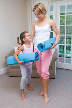 Mother and daughter with yoga mats at home in the living room