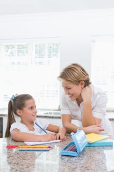 Mother and daughter doing homework at home in kitchen