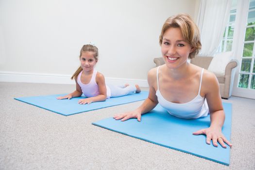 Mother and daughter doing yoga at home in the living room