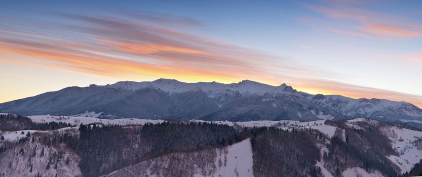 Alpine landscape with peaks covered by snow and clouds, view to Bucegi mountains. Panorama view.