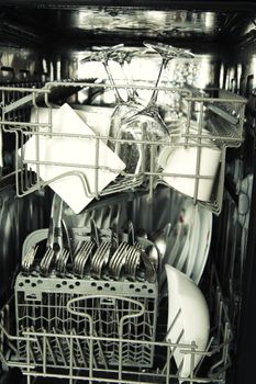 details of open dishwasher, utensils with drops in during washing