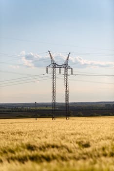 Large transmission tower with golden field and sky