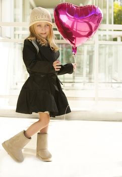 Portrait of a girl in black dress. Charming child with air baloons posing on white background indoors. Studio shot