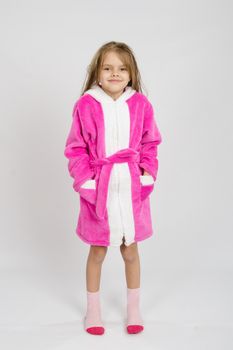 Six year old girl with wet hair in a bathrobe on a light background
