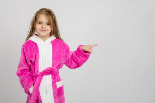 Six year old girl with wet hair in a bathrobe on a light background
