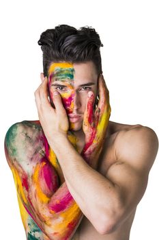 Attractive young man shirtless, skin painted all over with bright Holi colors isolated on white background