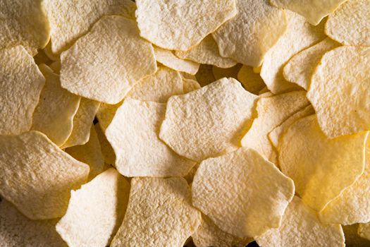 Close up background texture of golden oven baked potato chips for a tasty snack or appetizer viewed full frame from above