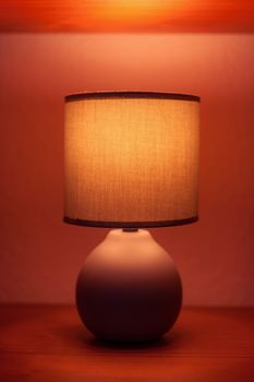Lit lamp on a shelf in moody light