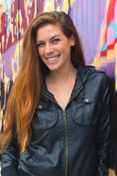 Portrait of a young woman in front of a colorful wall.